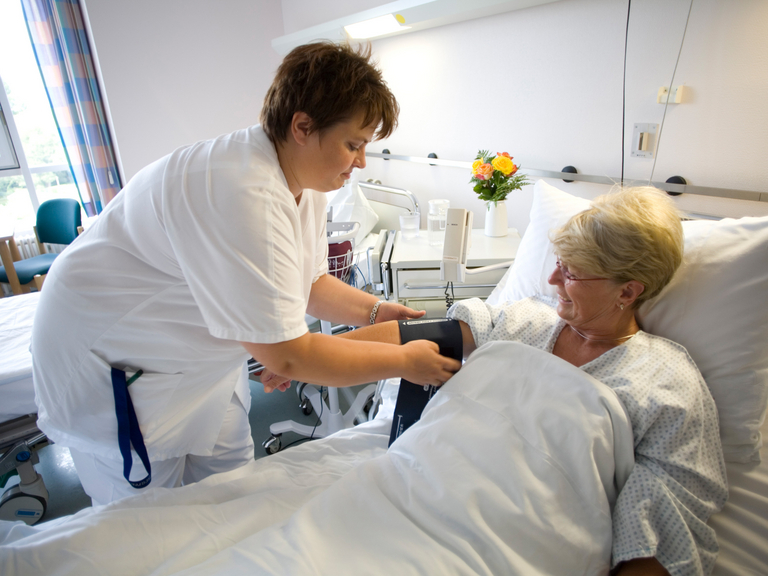Pflegefachfrau misst Blutdruck bei Patientin - Immanuel Klinikum Bernau - Versorgungsbereiche - Stationäre Behnadlung
