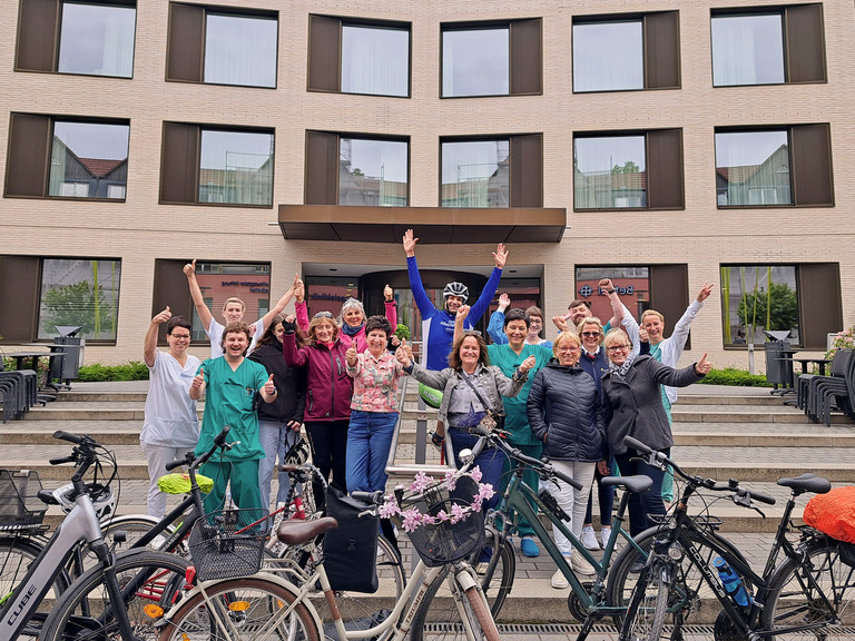 Das Team „Immanuel Klinikum & Netzwerk Gesunde Kinder radeln“ jubelt vor dem Krankenhaus zum 1. Platz beim Stadtradeln Bernau 2025 mit ihren Fahrrädern