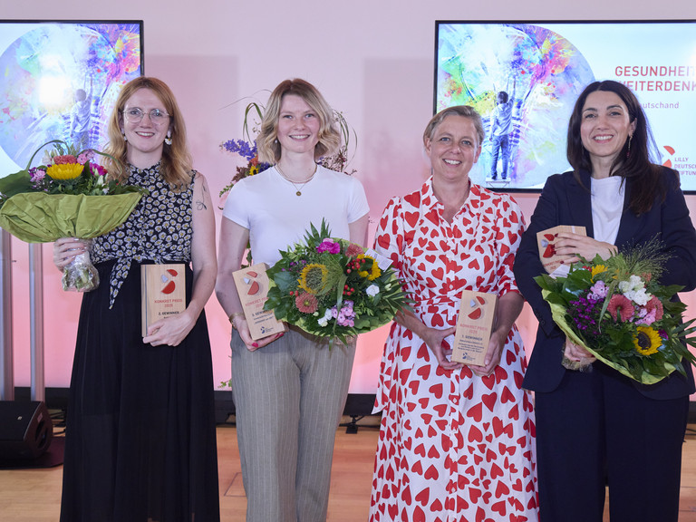 Die Gewinnerinnen stehen auf der Bühne nebeneinander mit Blumensträußen Die Gewinnerinnen stehen auf der Bühne nebeneinander mit Blumensträußen