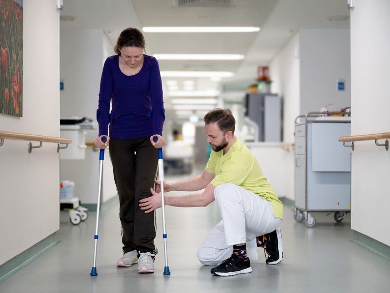Physiotherapeut mit Patientin mit Gehhilfe auf Gang Immanuel Klinikum Bernau bei Berlin - Physiotherapie